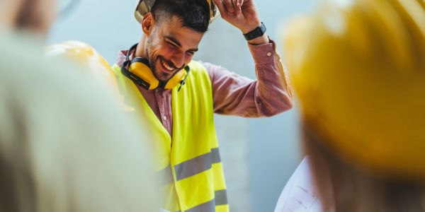 Smiling construction worker adjusting helmet.