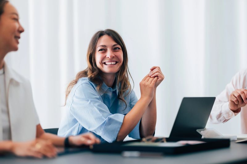 Casual workplace interaction featuring professionals collaborating in a relaxed atmosphere, emphasizing teamwork, positivity, and effective communication, complemented by a modern office setting and friendly facial expressions.