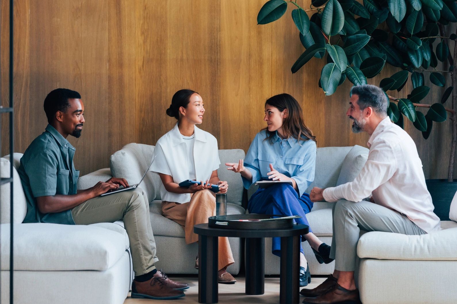 Four colleagues having a relaxed meeting in a cozy office lounge.