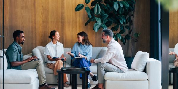 Four diverse professionals having a lively discussion in a modern office lounge.
