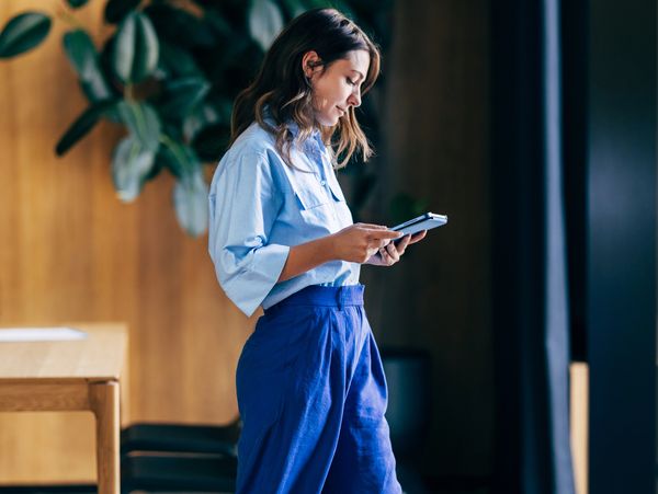 Woman standing and using a smartphone indoors.