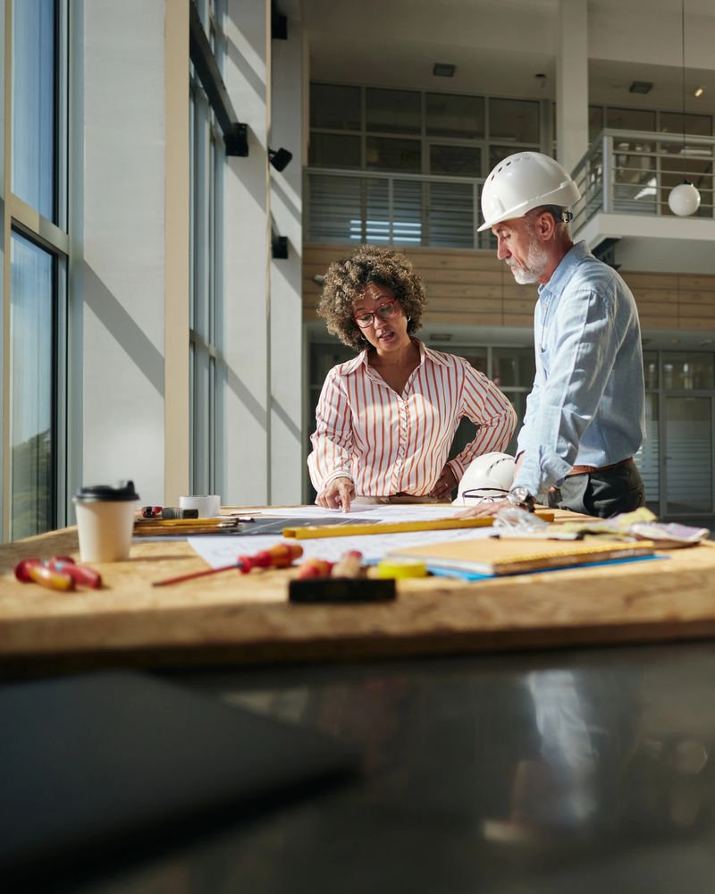 Diverse project managers cooperating while working on blueprints at construction building. Copy space.