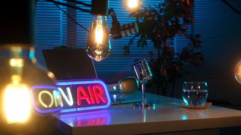 Vibrant podcast studio featuring a neon On Air sign, microphone, and ambient lighting on a desk.