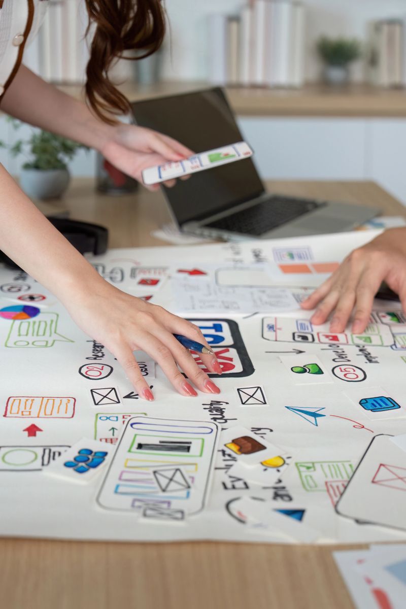 Close-up of designers' hands working on user interface sketches and digital concepts, emphasizing collaboration and creativity.