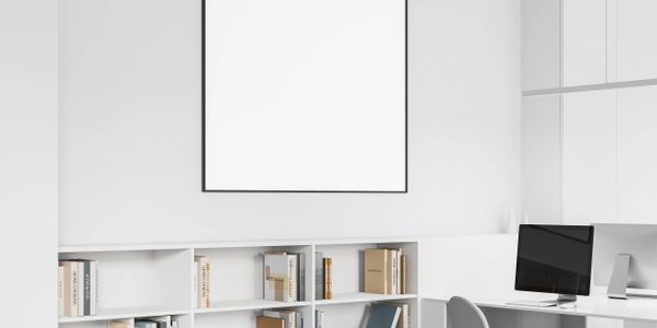 Minimalist office corner with white shelves, books, and a computer on a sleek desk.