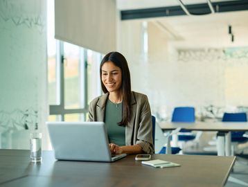 Woman working on a laptop at a desk in a modern office.