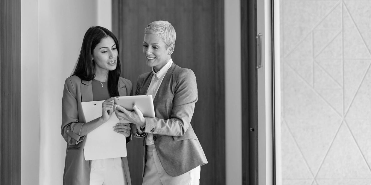 Dos mujeres profesionales revisan información en una tablet.