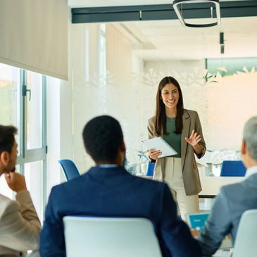 A woman in business attire giving a presentation to colleagues in a modern office.