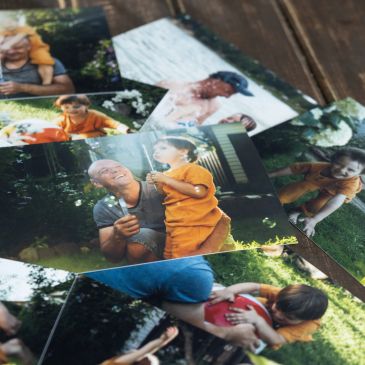 Printed photos scattered on a wooden surface.