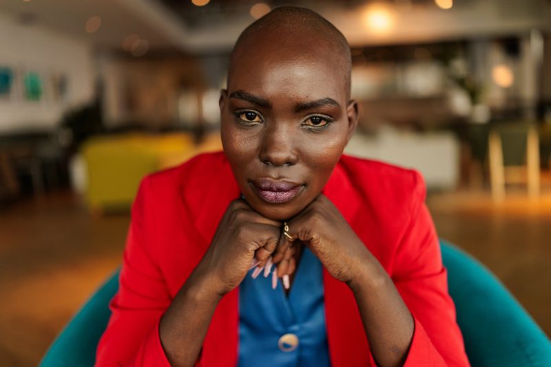 A confident and elegant businesswoman seated comfortably in an armchair, exuding professionalism and poise in a modern office setting.