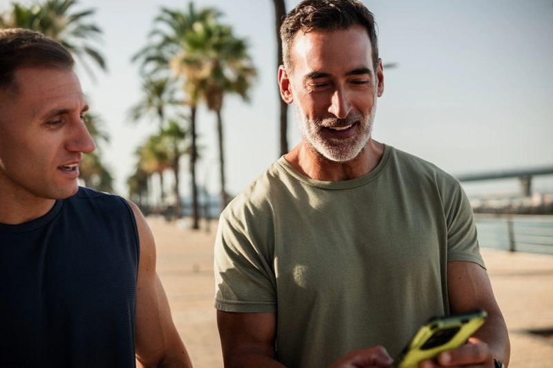 Two male athletes are checking their fitness app after a workout on a sunny day