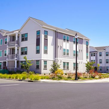 Modern three-story apartment buildings under a clear blue sky.