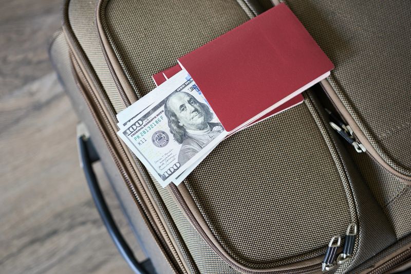 Suitcase with passport and dollars on wooden background. Travel concept