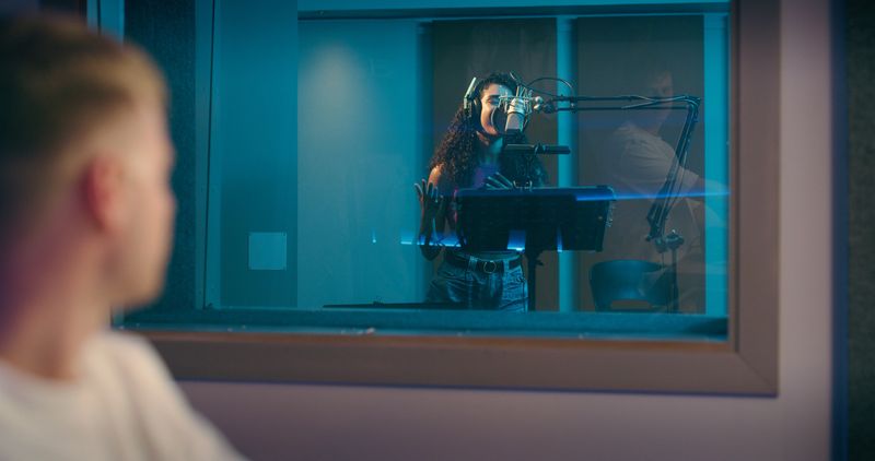 Recording studio, singer and woman with producer for singing songs, track and audio for album. Creative, musical industry and artist in booth with technician for performance, sound and rehearsal