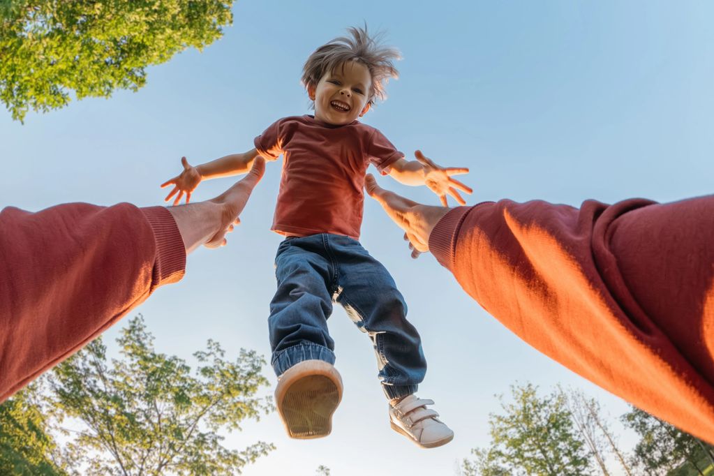 Child joyfully thrown in the air by an adult.