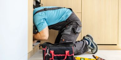 A plumber fixing pipes under a sink.