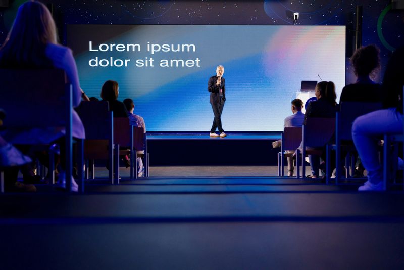Confident speaker addressing audience during a presentation at a modern professional event.