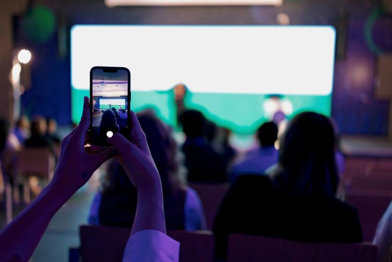 Audience member recording a technology presentation in a professional conference setting