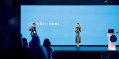Two presenters on stage at a conference.