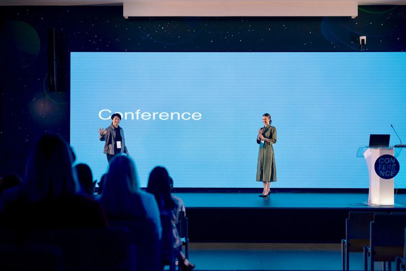 Professional Presenter Stepping onto Stage as Crowd and Host Watch