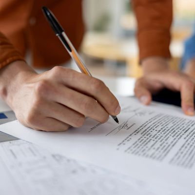 Person signing a document with a pen.