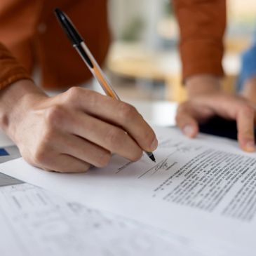 Person signing a document with a pen.