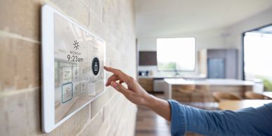 Person interacting with a smart home control panel on a wall.