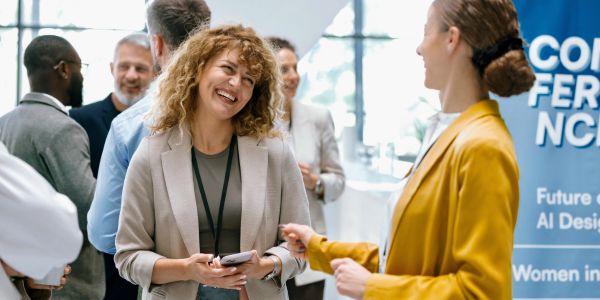 Two women smiling and talking at a conference.