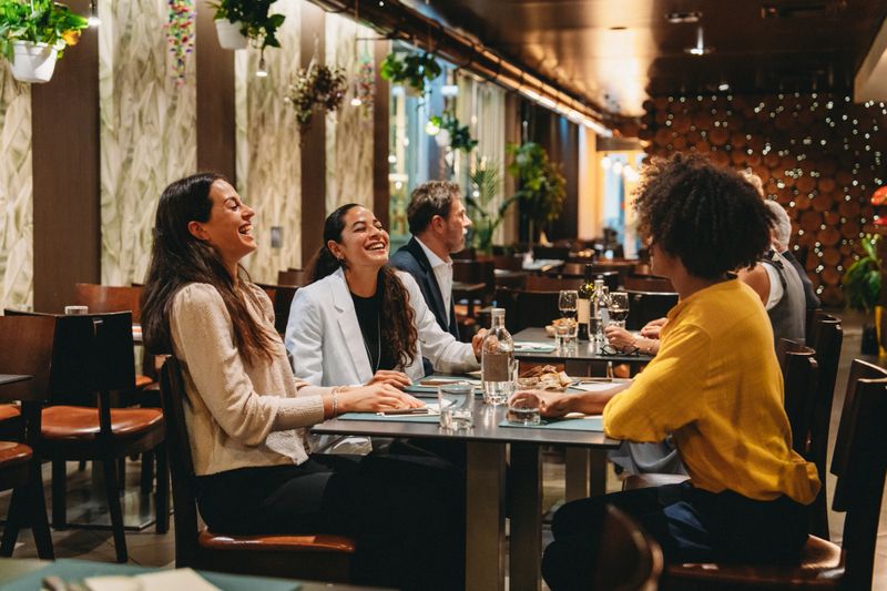 Cheerful businesswomen enjoying a business lunch together, laughing and talking in a modern restaurant
