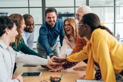 Diverse team joining hands in a collaborative meeting.