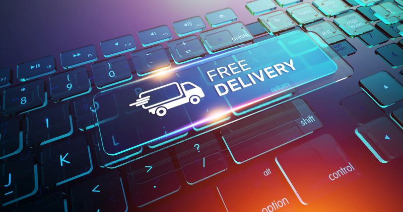 A futuristic keyboard features a glowing, transparent blue key with the words "FREE DELIVERY" and a fast-moving truck icon. This image is a powerful visual metaphor for modern E-commerce and Online Shopping, highlighting the popular customer incentive of free Shipping. The high-tech, illuminated design represents Innovation in Retail and Logistics. This concept is perfect for Online Advertising, promotional materials for a Sale, and articles discussing how Home Delivery services are improving the Customer Experience through Speed and Convenience.