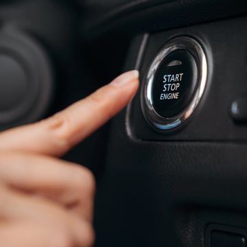 Finger about to press start-stop engine button.