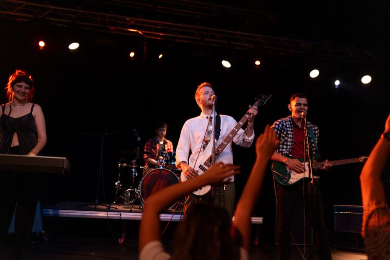 High-energy live show by a pop rock band under vibrant lights, nightclub crowd cheering