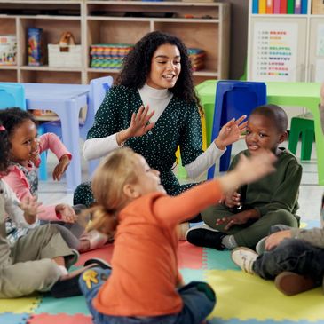 Teacher and kids playing on classroom floor.