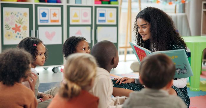 Preschool teacher reading a storybook to young children during circle time