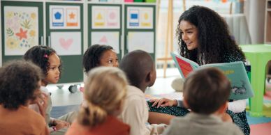 Teacher reading a book to children in a classroom.