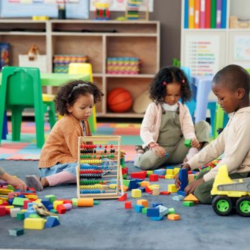Children playing with blocks and toys in a classroom.
