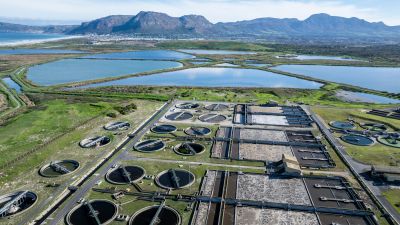 Aerial view of a wastewater treatment plant with surrounding lakes and mountains.