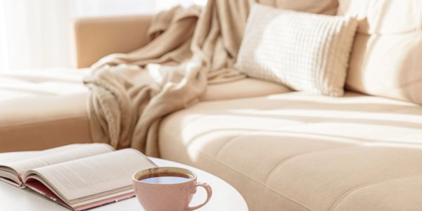 Cozy living room with beige sofa, coffee cup, and open book.