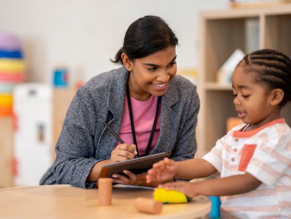 Teacher engaging a child in learning with blocks.