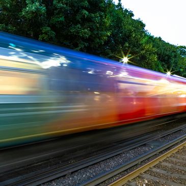 Blurred train speeding past tracks with greenery.
