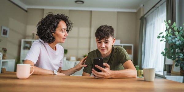 Woman and teenage boy looking at phone together.