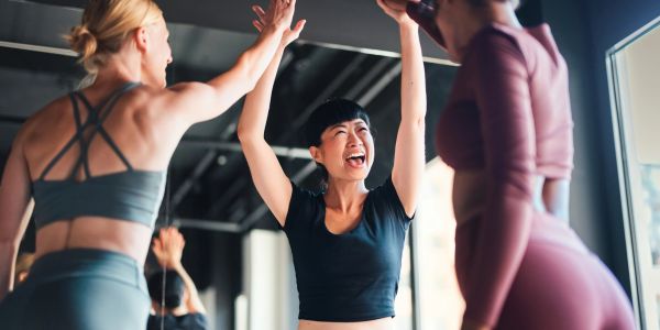 Three women celebrating at the gym with high-fives.