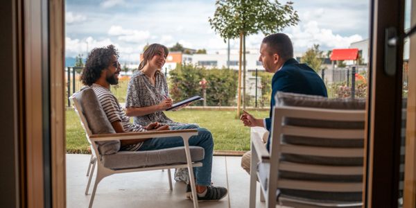 Three people having a friendly conversation outdoors on a patio.