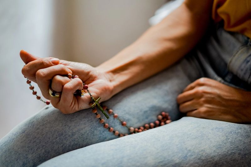 Close-up of a woman holding rosary during prayer time indoors