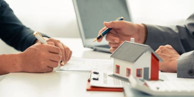 Two people discussing real estate with documents and a laptop.
