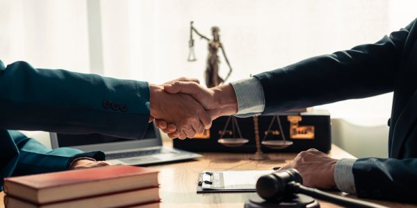 Two people shaking hands in a legal office setting.