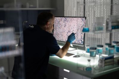 Scientist examining cells on a monitor in a lab.