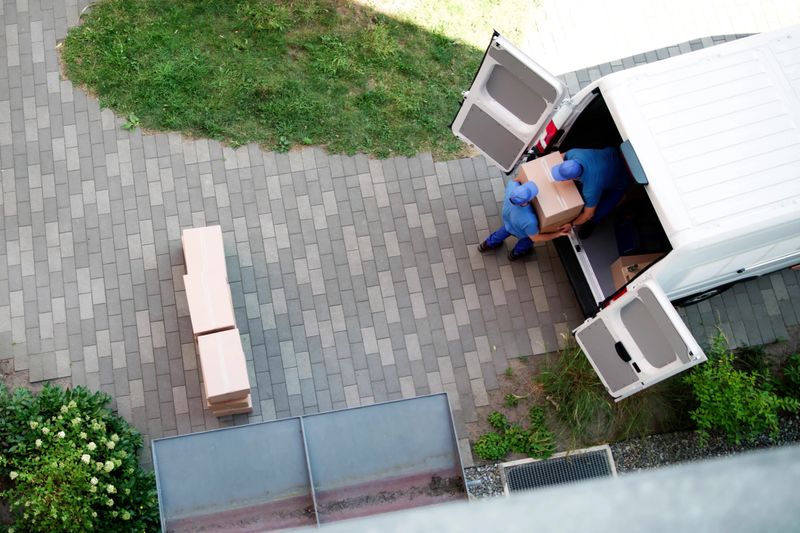 Happy Hispanic Mover Unloading Mattress From Furniture Delivery Truck Today.