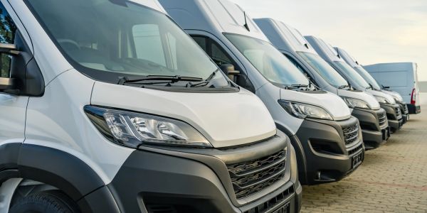 Row of white delivery vans parked side by side.